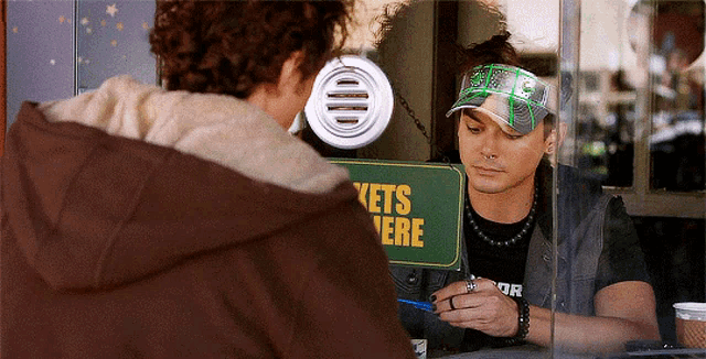 a man standing in front of a tickets here sign