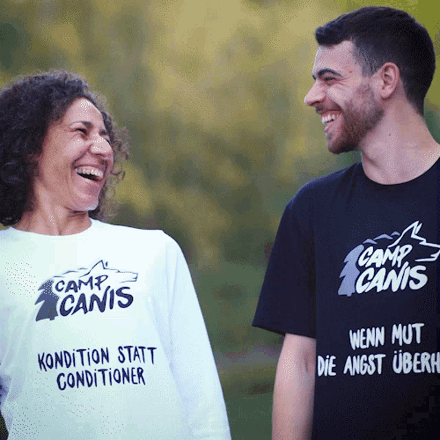 a man and a woman wearing camp canis shirts are laughing