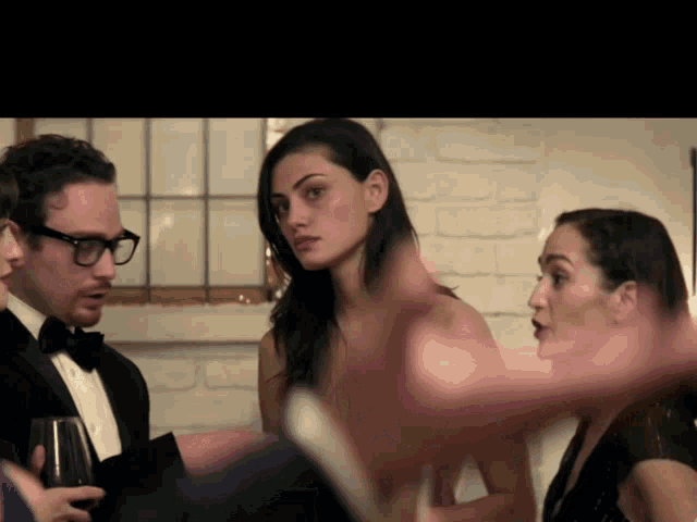 a man in a tuxedo is talking to a woman in a black dress