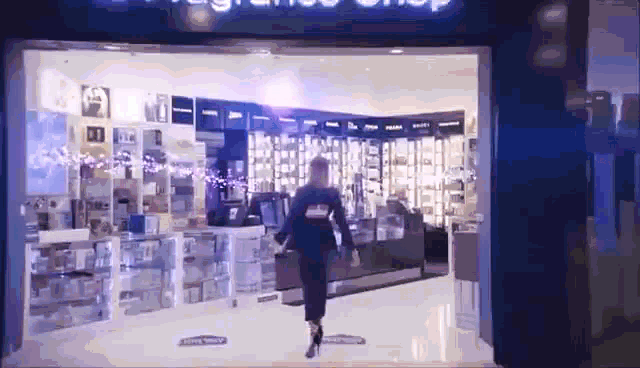 a woman is walking out of a store with a sign that says ' fragrance shop ' on it