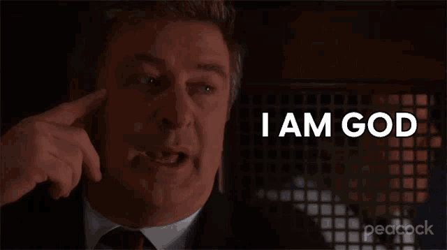a man in a suit and tie is pointing at his head and saying i am god