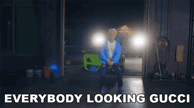 a man in a blue jacket is standing in front of a green car with the words everybody looking gucci above him