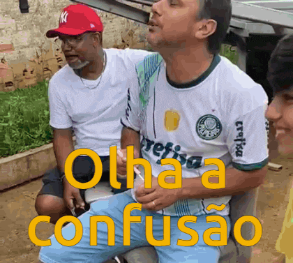 a man wearing a palmeiras shirt is sitting next to another man