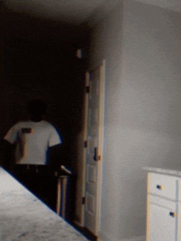 a blurry picture of a person standing in a dark room with a white door