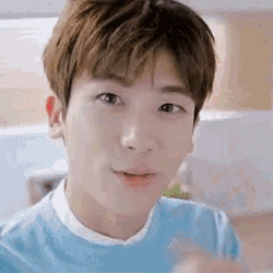 a close up of a young man 's face wearing a blue shirt and smiling .