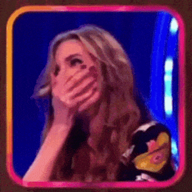a woman is covering her mouth with her hand in a pink and blue frame .