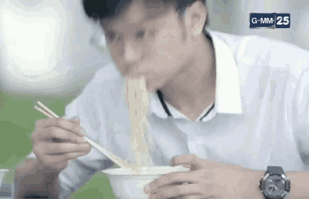 a young man is eating noodles with chopsticks .