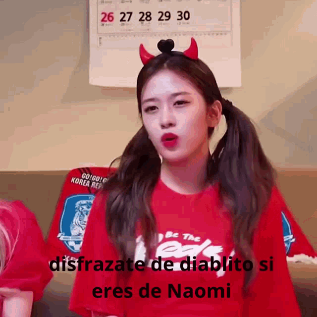 a girl wearing devil horns and a red shirt that says be the red