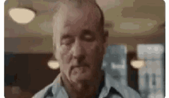 a close up of a man with his eyes closed in a restaurant .