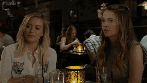 two women are sitting at a table in a restaurant with #youngertv written on the bottom right corner