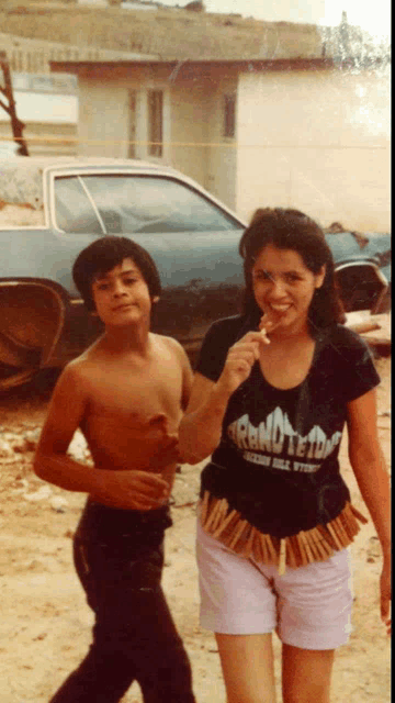 a woman wearing a shirt that says rancho teton is standing next to a boy