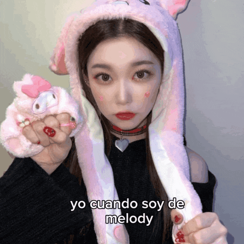 a girl wearing a pink bunny hat holds a stuffed animal in her hand