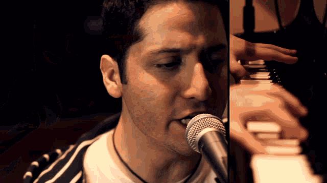 a man singing into a microphone next to a man playing a piano