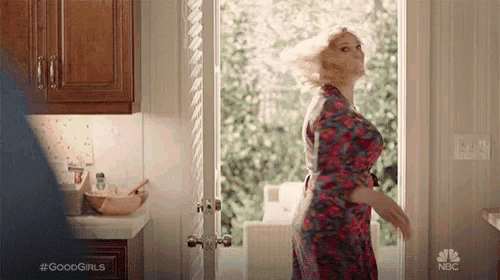 a woman in a robe is standing in front of a kitchen door .