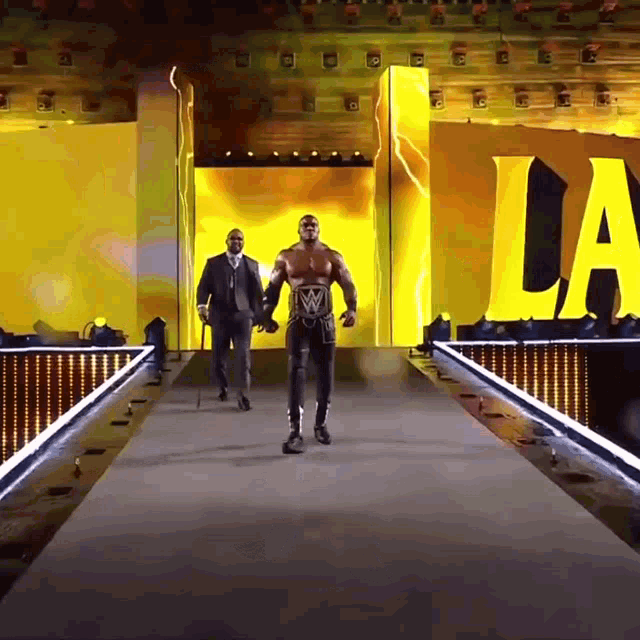 a wrestler is walking down a ramp with a yellow sign that says la on it