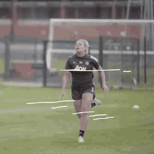 a female soccer player wearing an aon jersey is running on a field .