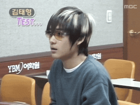 a young man wearing sunglasses sits in front of a sign that says test on it