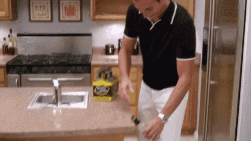 a man in a black shirt is standing in a kitchen with a box of gatorade on the counter