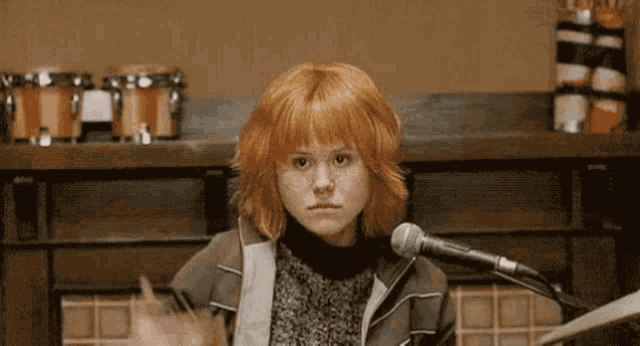 a girl with red hair is singing into a microphone
