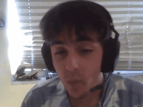 a man wearing headphones with a microphone looks at the camera