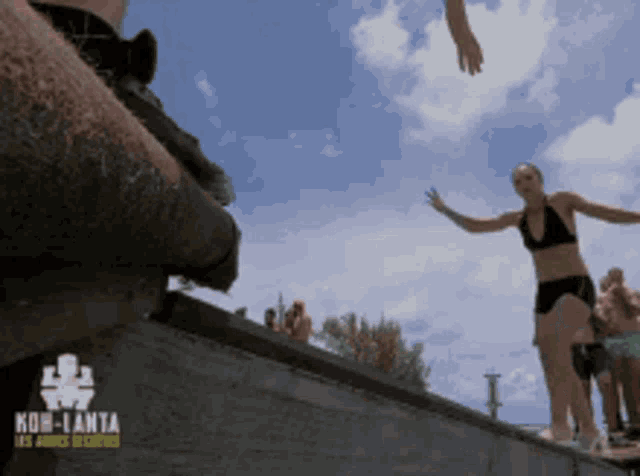 a woman in a bikini is jumping into a pool with a koh-lanta logo on the bottom