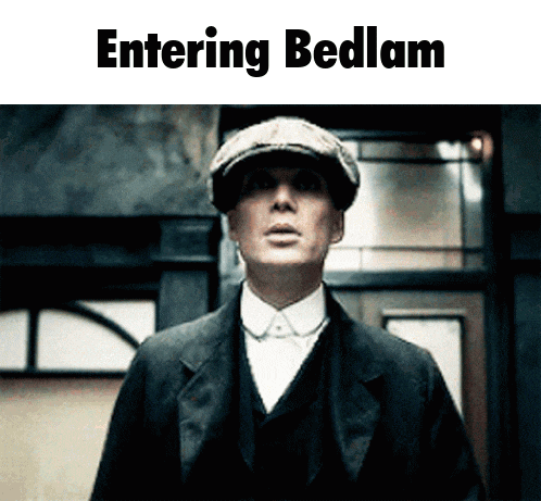 a man in a suit and hat is standing in front of a sign that says " entering bedlam "