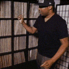 a man in a black shirt is standing in front of a shelf of records