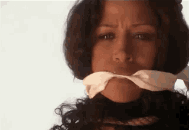 a woman with a rope around her neck has a white cloth around her mouth .
