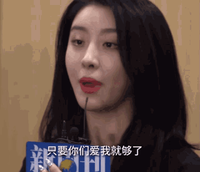 a woman speaking into a microphone in front of a sign that says ' news '