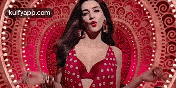 a woman in a red dress is standing in front of a circular pattern and making a funny face .