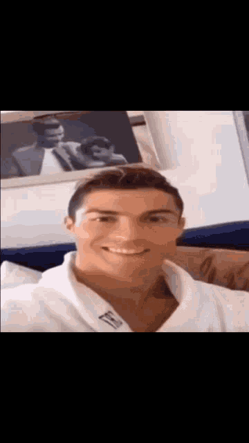 a man in a white robe smiles in front of a picture of a man and woman