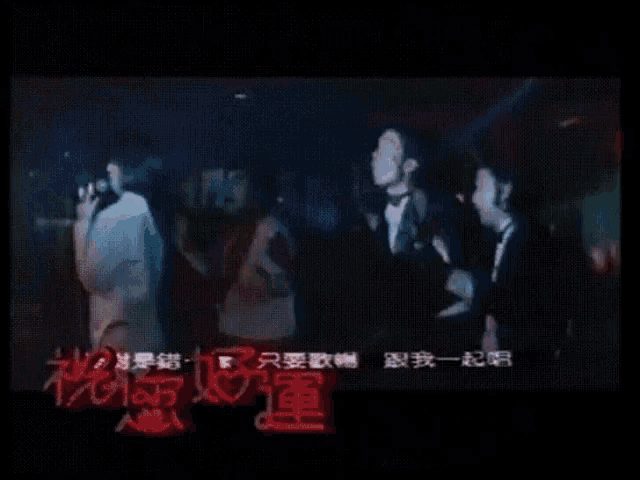 a group of men in tuxedos are dancing in a dark room with chinese writing on the bottom