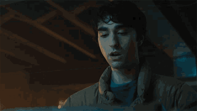 a man in a dark room is looking at a laptop