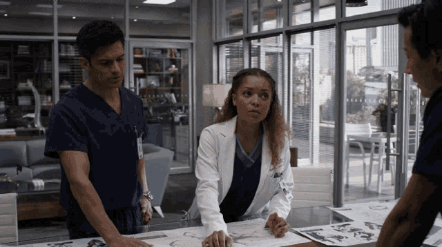 a group of doctors are looking at a drawing on a desk