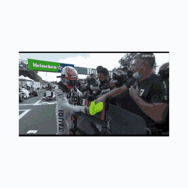 a race car driver shakes hands with a crowd in front of a heineken banner