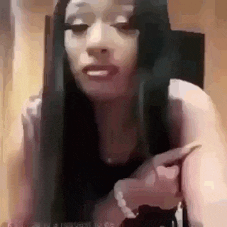 a woman with long black hair is sitting in a chair and talking on a cell phone .