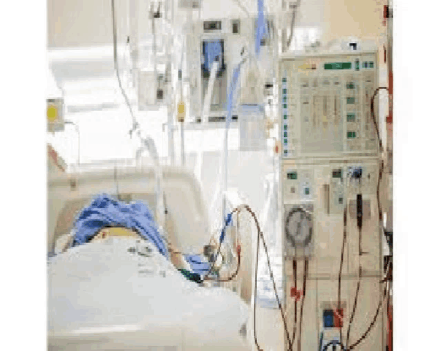 a person is laying in a hospital bed with a dialysis machine in the background .