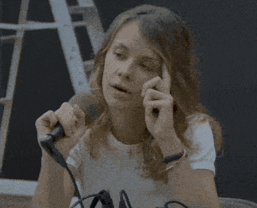 a woman in a white shirt is holding a microphone in her right hand
