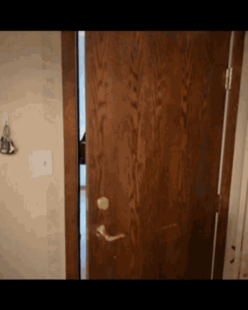 a wooden door is open in a room with keys hanging on the wall