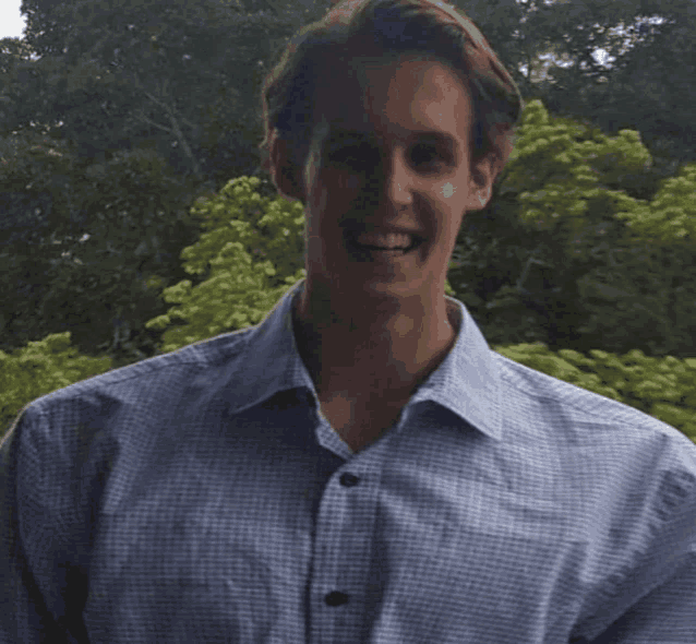 a man wearing a blue plaid shirt smiles for the camera