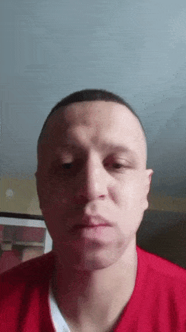 a man in a red shirt is looking at the camera with his eyes closed
