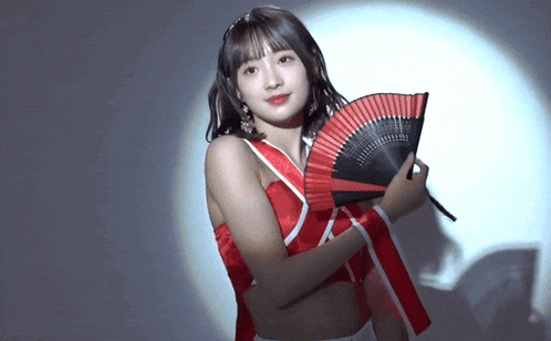 a woman in a red top is holding a fan in her hand