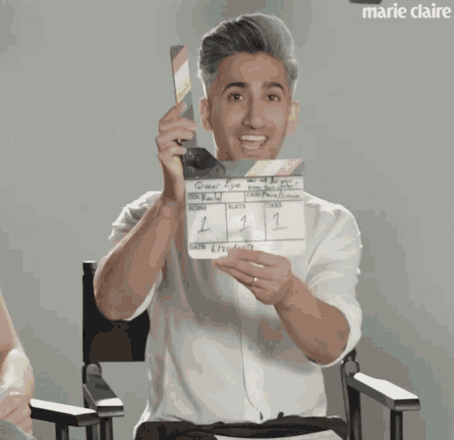 a man in a white shirt is holding a clapper board with the numbers 1 and 2 on it