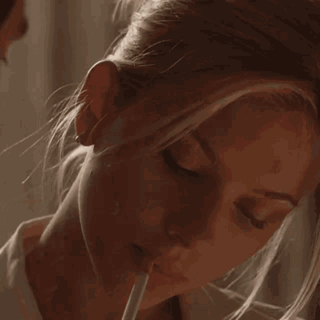 a close up of a woman smoking a cigarette with smoke coming out of her mouth