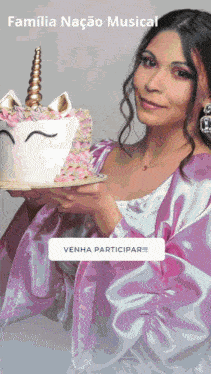 a woman in a pink dress is holding a unicorn cake in her hands