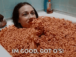 a woman is laying in a bathtub filled with macaroni and cheese