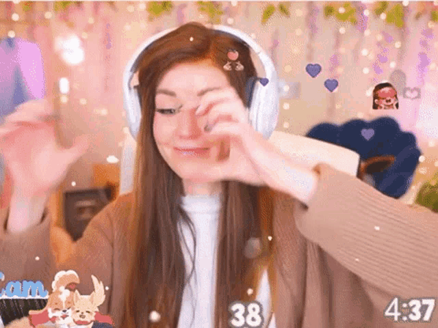 a woman wearing headphones is making a heart shape with her hands while playing a video game .