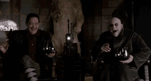 two men are sitting next to each other holding wine glasses and smiling .