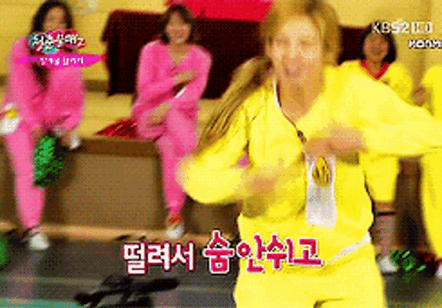 a woman in a yellow sweatshirt is dancing in front of a group of women