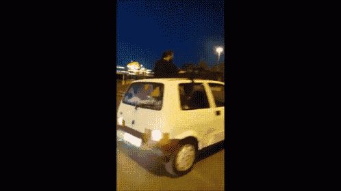 a man is standing on top of a white car